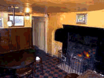 This room contains an old built-in range with an open coal fire. High-backed bench seats surround an old round table, whilst another rickety, very-old long wooden table stands near the window in a very unsober fashion upon the red and black tiled floor.